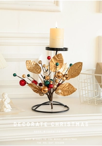 Christmas iron candle holder with golden leaves, colorful berries and lit candle