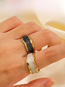 Detail view of wavy gold-plated rings with dark blue and pearly white enamel on finger