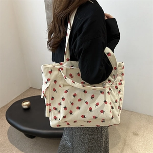 Beige corduroy tote bag with red strawberry pattern featuring multiple utility pockets