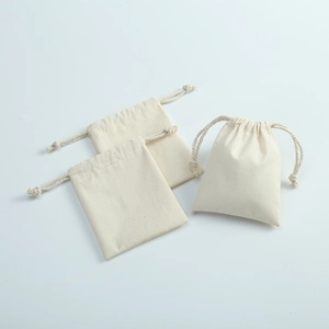 Close-up of three beige cotton linen drawstring pouches with visible fabric texture