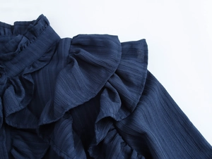 Detailed macro view of dark blue ruffled collar and pleated fabric texture on blouse