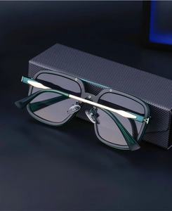 Detail of square frame sunglasses with gold metal accents on a carbon fiber case