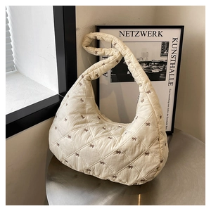 Nahaufnahme der beige gesteppten Hobo-Tasche mit brauner Schleifenstickerei