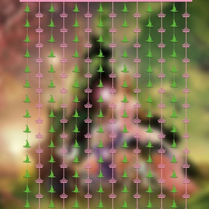 Glittery pink tinsel curtain backdrop featuring green witch hats and pink crown motifs