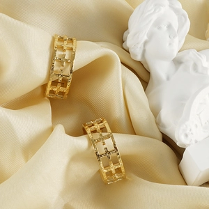 Classic gold titanium steel hollow cross earrings on elegant silk background