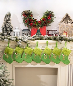 Close-up of seven green knit Christmas stockings spelling WELCOME on a white fireplace