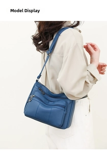 Blue soft leather crossbody bag with multiple front zipper pockets worn by a model