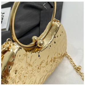 Detail showing the golden hammered metal texture and round handle of this evening clutch bag