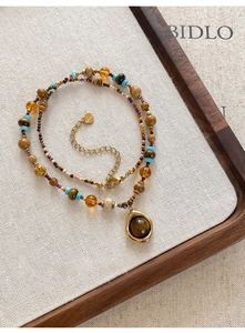 Gros plan d'un collier de perles bohème avec fermoir doré et pendentif rond turquoise