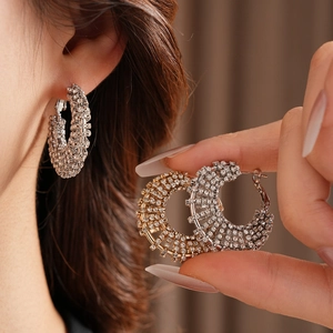Detailed close-up of gold and silver rhinestone hoop earrings shown on a model