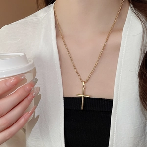 Close-up of 18k gold plated cross necklace on model with minimalist figaro chain design