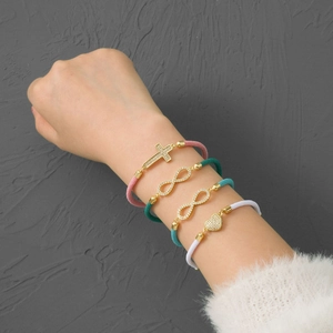 Set of four woven bracelets with gold infinity, cross, and heart charms with crystals