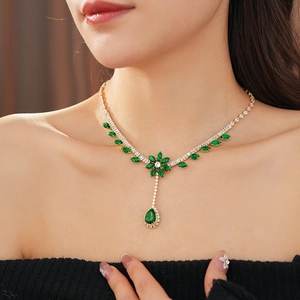 Close-up of sparkling green zircon flower and teardrop pendant necklace on model