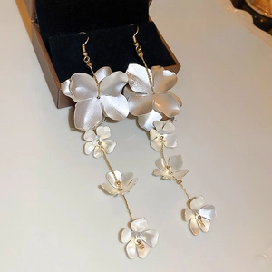 Macro detail of long flower tassel earrings featuring matte silver petals and gold chains