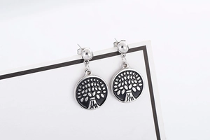Close-up of silver steel earrings featuring a black Tree of Life pattern on a white card