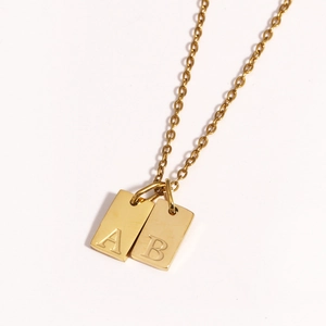 Close-up of gold plated square pendant charms featuring engraved letters A and B