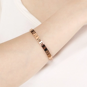 Gros plan d'un bracelet ajouré or rose avec chiffres romains porté sur le poignet