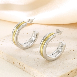 Vue macro de boucles d'oreilles épaisses en C bicolores en argent et or polis