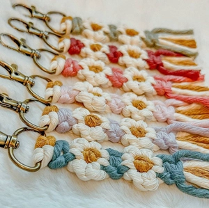 Vue macro de cinq porte-clés fleurs en macramé faits main sur un fond en fourrure blanche