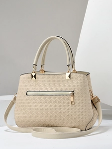 Close-up of beige woven texture and gold metal hardware on the women's handbag