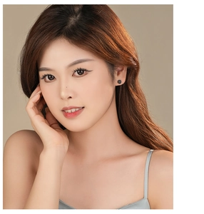 Close-up of a model wearing minimalist round black onyx stud earrings in S925 silver