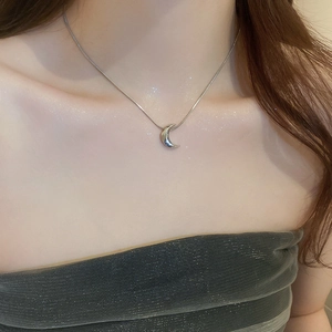 Close-up of silver crescent moon pendant on a thin snake chain necklace for women