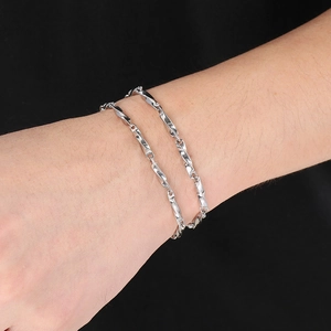 Polished silver stainless steel twisted Chopin chain bracelet on wrist close-up view