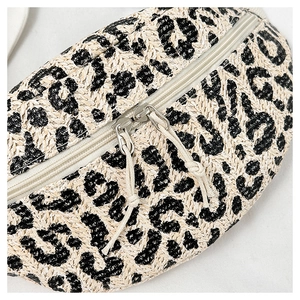 Close-up of woven leopard print fanny pack featuring straw texture and double zippers