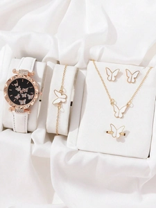 Close-up of butterfly jewelry set with white leather strap watch on silk fabric