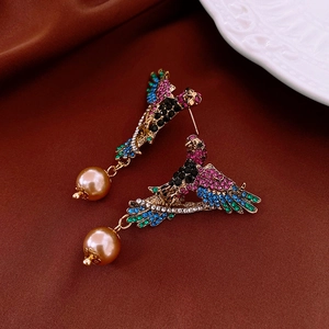 Close-up of vintage parrot earrings with colorful crystals and large champagne pearls