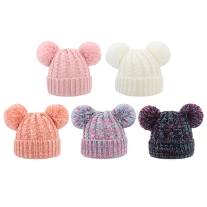 Close-up of winter knit beanies with double faux fur pom-poms in various colors