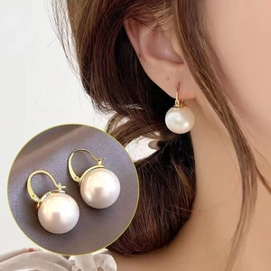 Detail of French vintage round pearl earrings with elegant gold U-shaped hooks for women