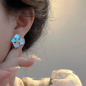 Elegant floral stud earrings with blue-white shell petals and zircon center on the ear