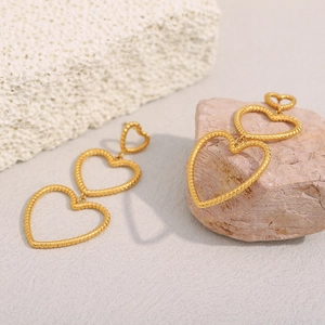Close-up of triple intertwined gold heart earrings with twisted rope texture detail