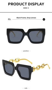 Detail view of oversized black square sunglasses featuring a signature gold chain temple
