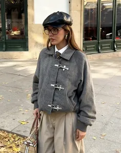 Detalle de chaqueta de lana gris con hebillas metálicas y diseño de estilo universitario