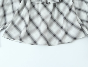 Detailed view of the ruffle hem and black and white plaid pattern on women blouse