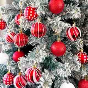 Detail of red and white patterned Christmas ornaments hanging on a snowy tree branch