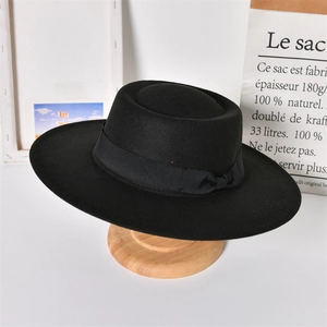 Detail of a vintage black wool felt boater hat with a wide brim and decorative ribbon bow