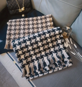 Detail shot of two thick houndstooth scarves with fringes on a luxury leather sofa