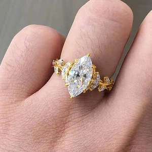 Macro shot of marquise-cut zircon ring with gold vine leaf design on a finger