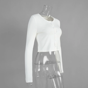 Detail of white ribbed knit fabric texture and buttons on a slim-fit cropped cardigan