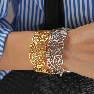 Gros plan d'un large bracelet manchette papillon évidé en métal doré sur un poignet