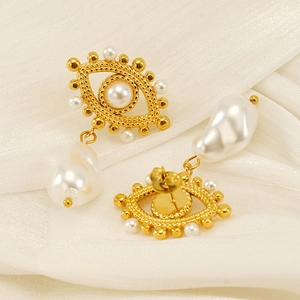 Evil eye gold earrings with pearl accents and baroque pearl drops on white silk fabric
