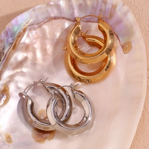 Dettaglio di orecchini a cerchio aerodinamici lucidi in oro e argento coordinati