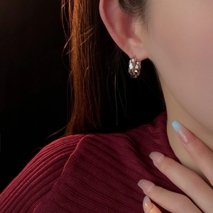 Detail of silver textured hoop earring with irregular hammered finish on model