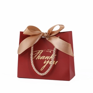 Burgundy gift bag with champagne gold ribbon bow and golden Thank You lettering