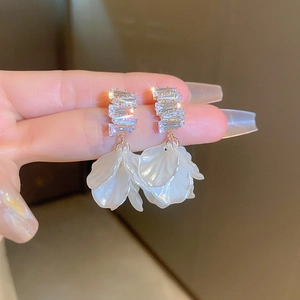Macro view of crystal rhinestone stud and layered white petal fringe on flower drop earrings