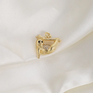 Macro shot of gold sloth pendant with clear crystals on white silk background