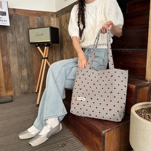 Détail d'un sac cabas en toile avec pois rouges et nœuds sur motif à carreaux